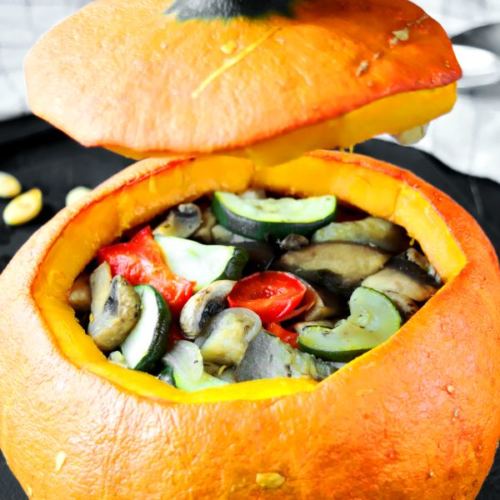 Stuffed pumpkin with baked vegetables is beautiful and healthy meal. Orange pumpkin, stuffed with zucchini, eggplant, mushrooms and red bell pepper.