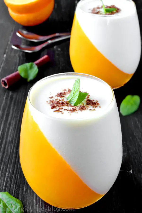 Orange panna cotta is creamy and fresh dessert, one of the Christmas dessert ideas you can make for your family. Easy no bake desserts that you will enjoy! Orange and white dessert, served with peppermint leaves and shredded chocolate.