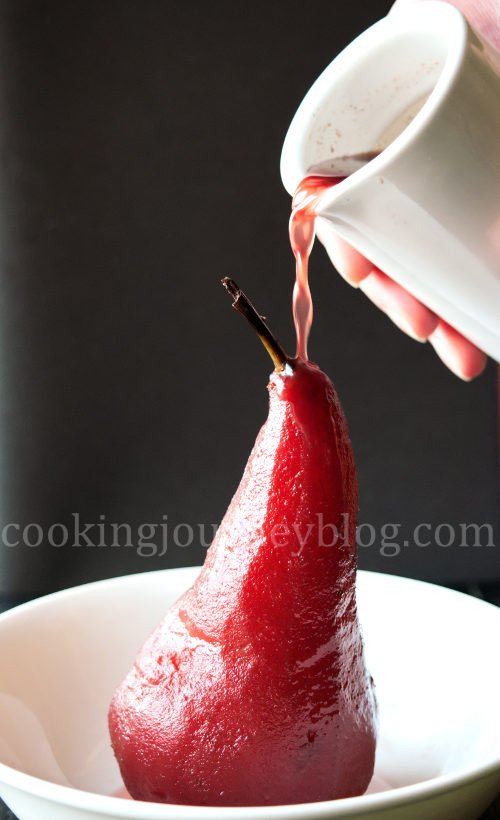 Poached pears is an easy and exquisite French dessert. This is no bake dessert, spicy poached pears in red wine. To my mind, this is one of the most beautiful pear desserts - soft fruit with spicy winter flavors. Poached pear in red wine, served on the white plate, poaring the wine sauce on top.