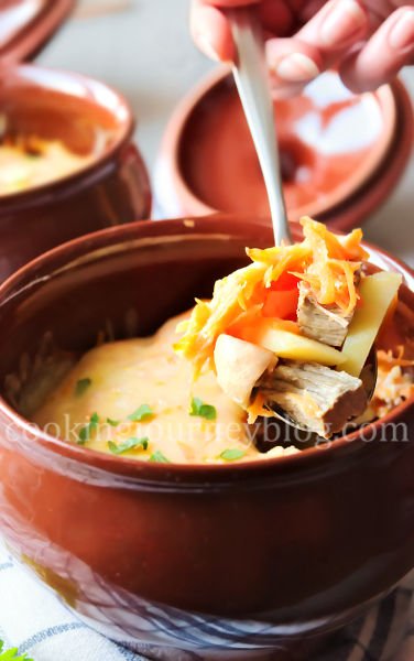 Dinner Ideas . Dinner in a clay pot. Beef and potatoes, covered with cheese and parsey in a spoon.