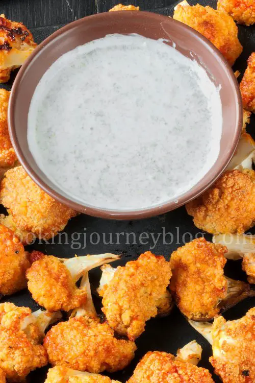 Buffalo cauliflower on a black board, served with white sauce
