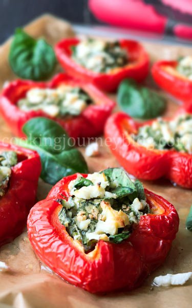 Red bell peppers stuffed with feta and spinach on a baking tray