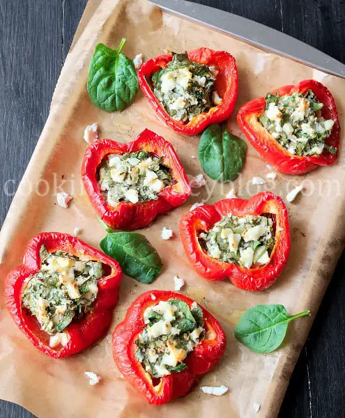Red bell peppers stuffed with feta and spinach on a baking tray