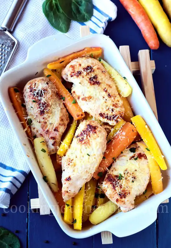 Baked chicken breasts and roasted carrots in a baking dish