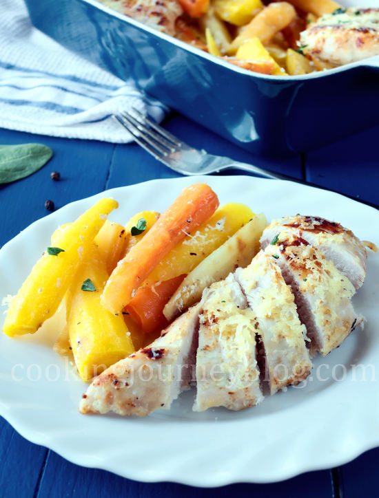 Baked chicken breast, cut and served on a white plate with colorful roasted carrots
