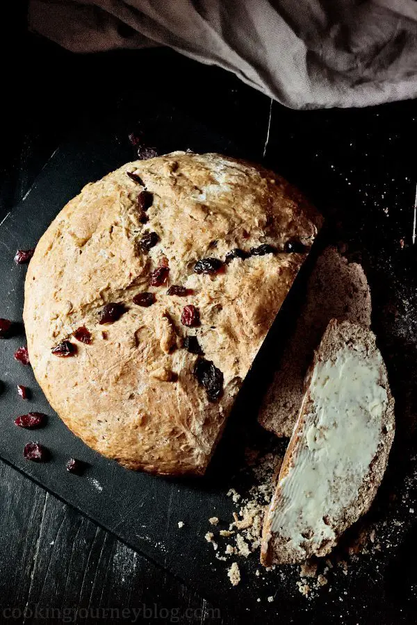 Irish soda bread with buttter and cranberries on a black board. View from top.