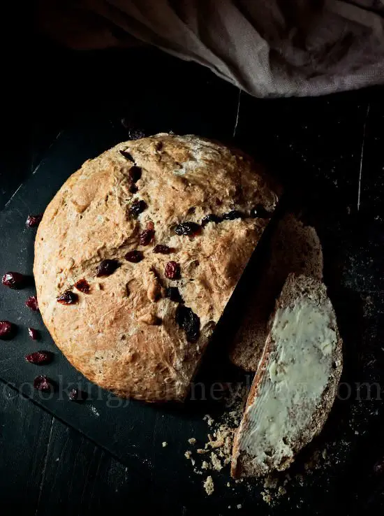 Irish soda bread with buttter and cranberries on a black board. View from top. Light from the window.