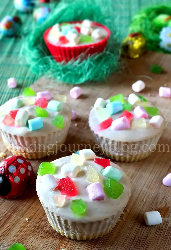 Easter desserts - mini cheesecakes with colorful marshmallows, served with Easter chocolate on a wooden board