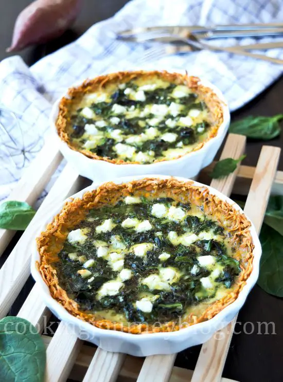Spinach Quiche Recipe - How To Make Quiche. Spinach quiche, served on wooden board on the black table. Sweet potato on the background