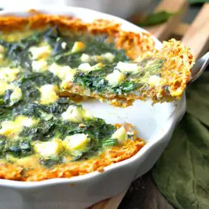 A slice of spinach quiche on a fork.