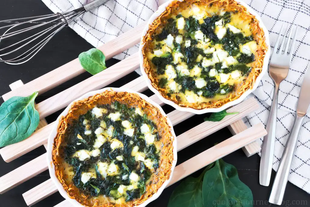Spinach quiche, served on wooden board on the black table