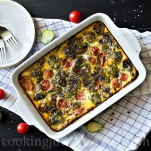 Breakfast frittata with mushrooms, Brussels sprouts and tomatoes, served on a black table right from the oven