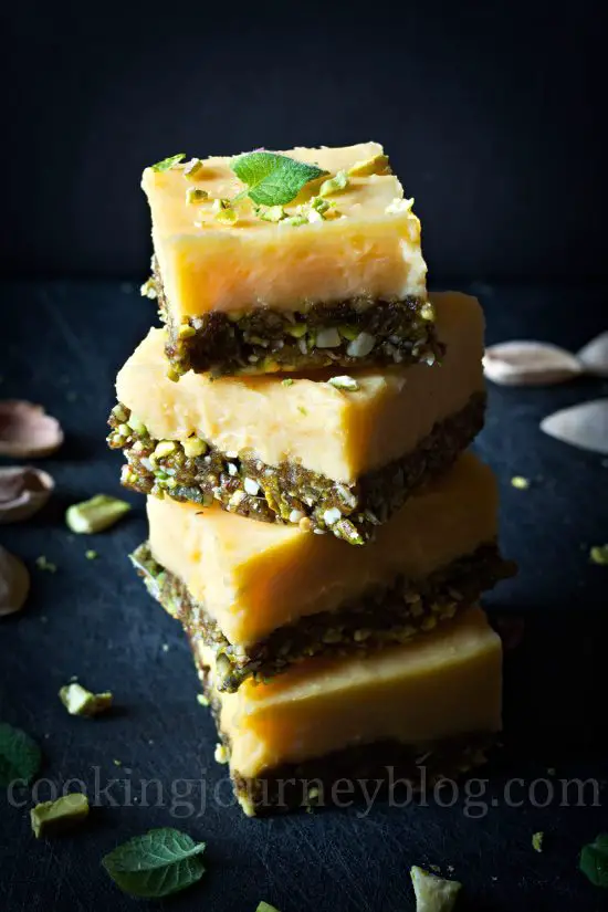 Lemon squares, stack on the black board with pistachios and mint