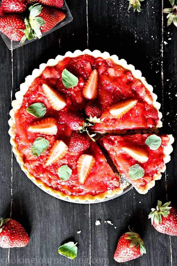 Red strawberry tart with fresh strawberries and mint leaves, sliced
