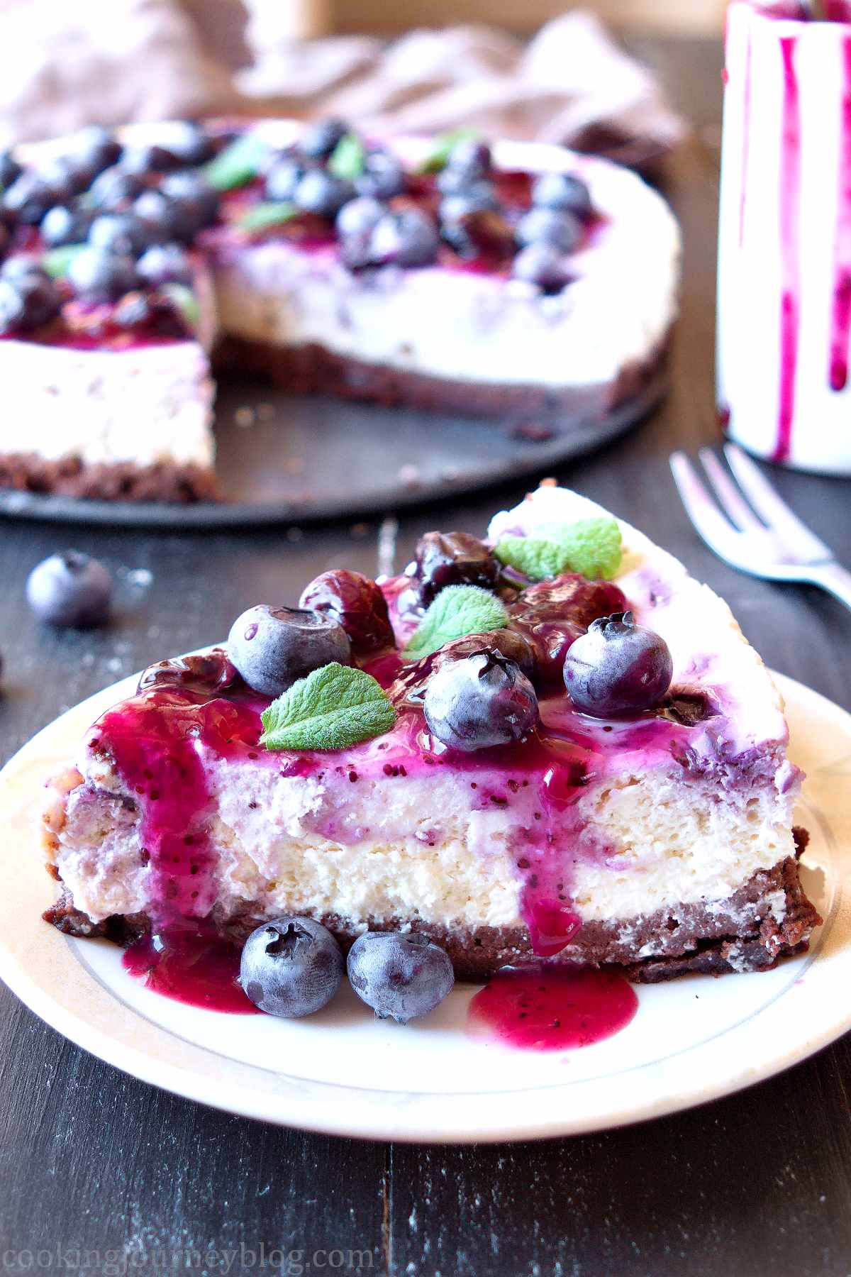 Blueberry cheesecake with chocolate biscuit crust and fresh blueberries and mint on top