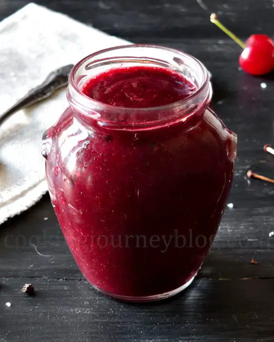 Fresh cherry sauce in a jar on the black table