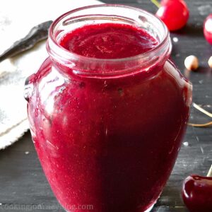 Cherry sauce in a jar on the black table, opened