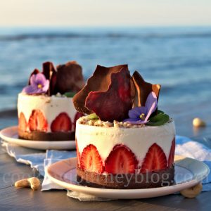 No Bake Greek Yogurt Dessert, decorated with chocolate and strawberries, on a white plate on the seaside
