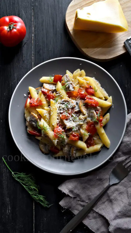 Creamy Mushroom Pasta with Tomatoes, cheese and dill, served on gray plate