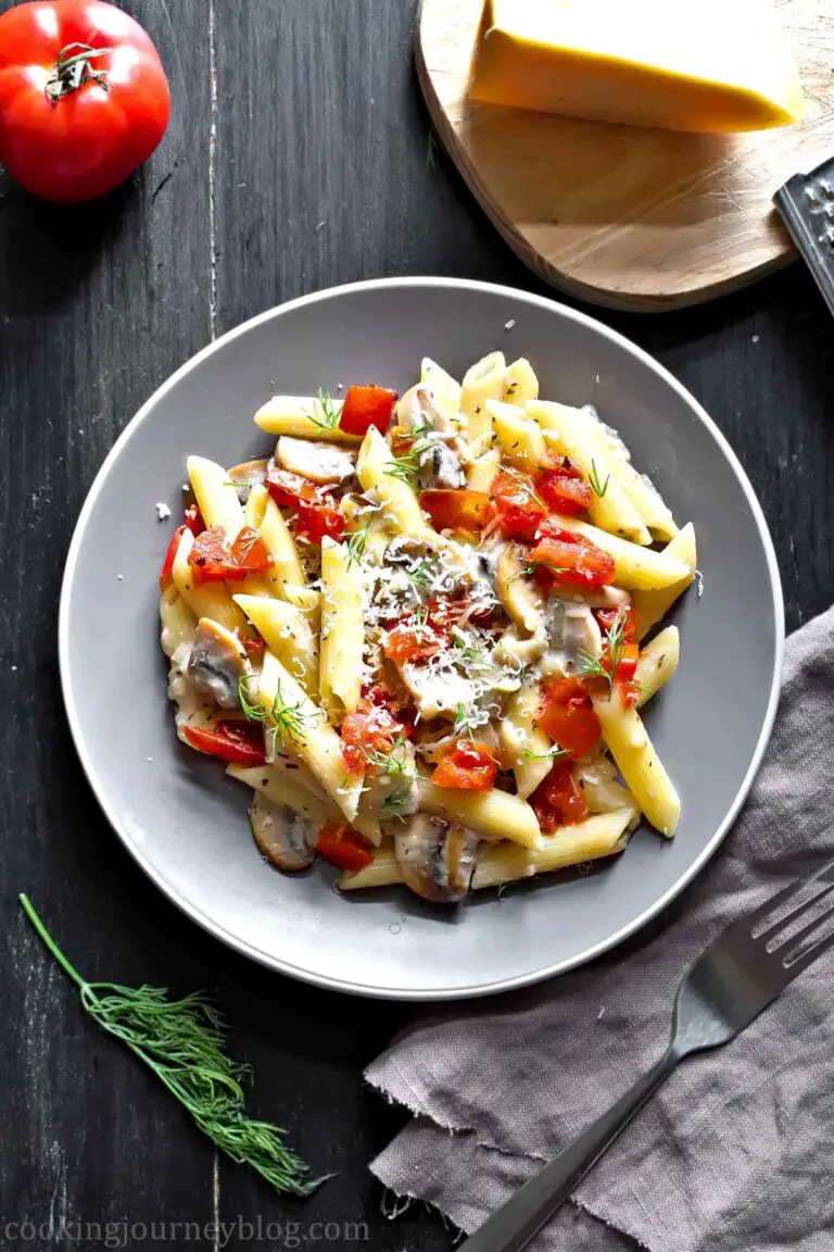 Creamy Mushroom Tomato Pasta with cheese and dill, served on gray plate