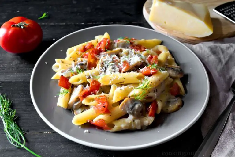 Creamy Mushroom Pasta with Tomatoes, cheese and dill, served on gray plate