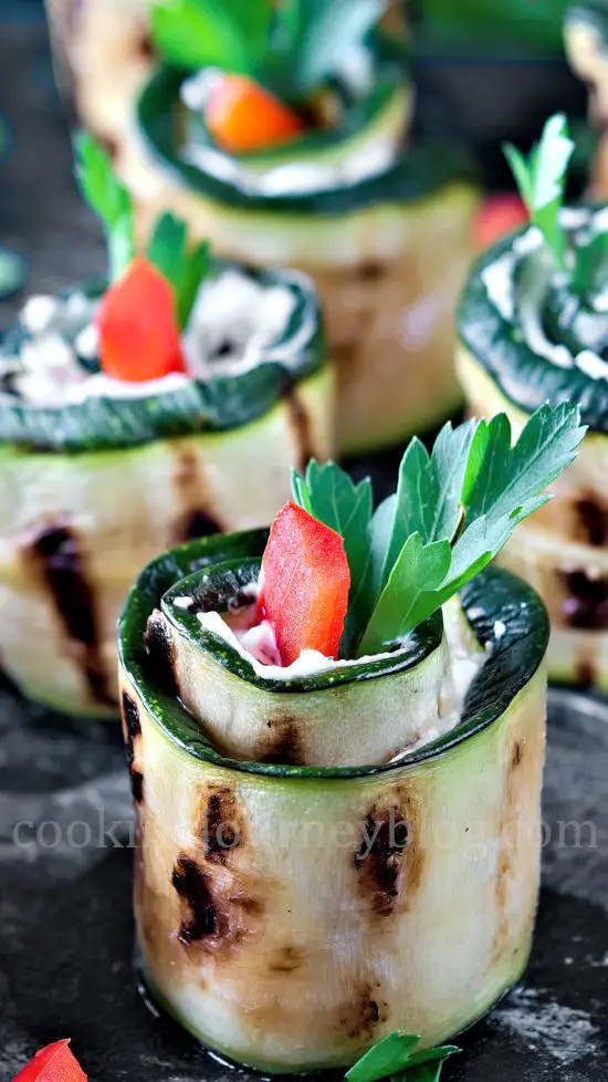Grilled Zucchini Roll Ups with rerd bell pepper and parsley on black table