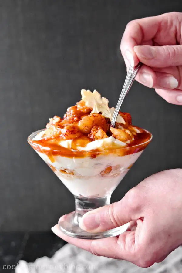 Holding caramel apple trifle in hands with a spoon
