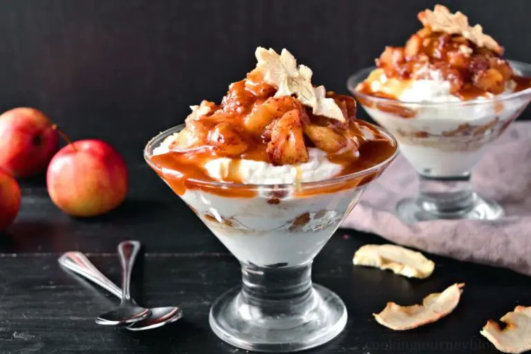 Caramel Apple Trifle with cinnamon apples, whipped cream and dried apples, placed on the black table with spoons