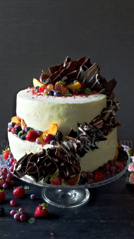 Peach cake with cream cheese frosting, decorated with chocolate and fruits.