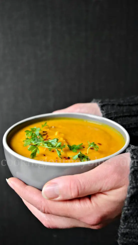 Holding Healthy Vegan Carrot Ginger Soup in hands