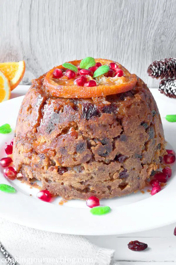 Christmas Pudding, served on a plate with pomegranate seeds and orange, served on the plate.