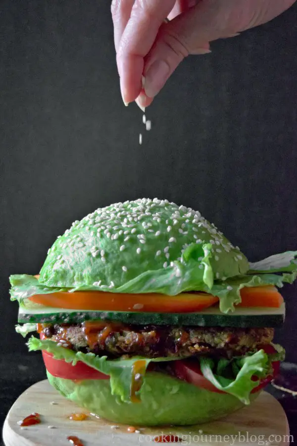 Sprinkling sesame seeds on vegan avocado burger