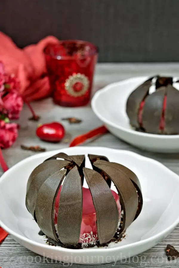 Mirror glaze cake, hidden under chocolate leaves. Valentine's desserts served on a white plate.