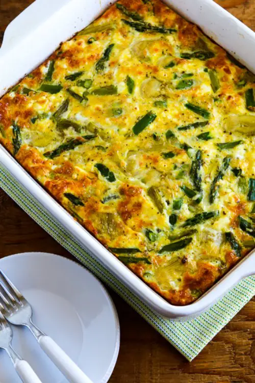 Casserole with asparagus and artichoke served with plates and forks
