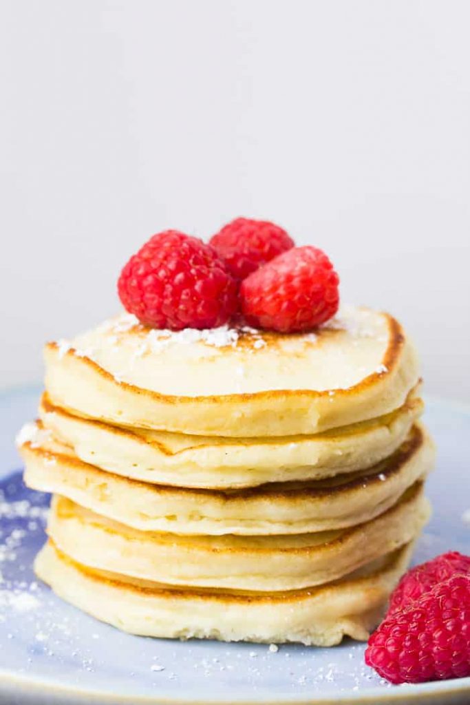 Lemon Pancake stack on a white plate, decorated with raspberries