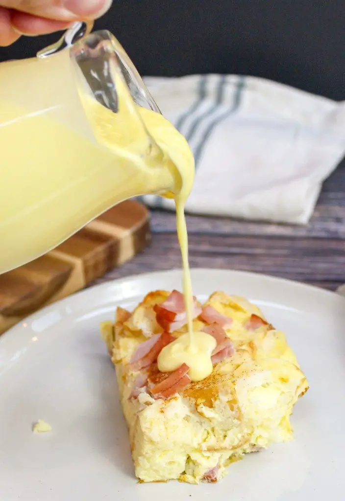 Pouring sauce on Eggs Benedict Casserole