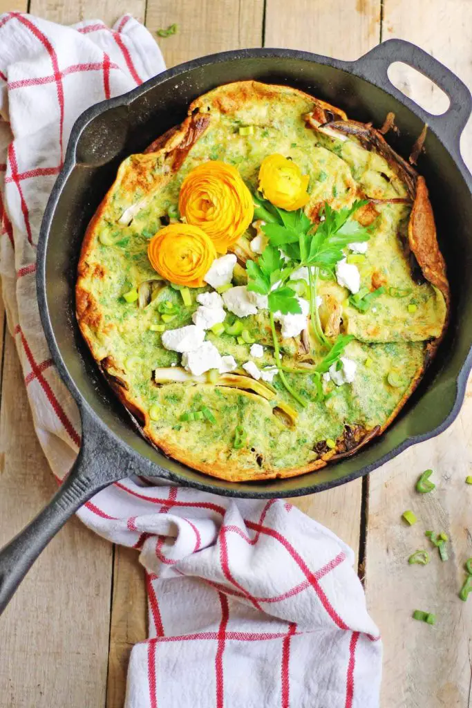 Spring onion dutch baby with herbs and goat cheese in a pan