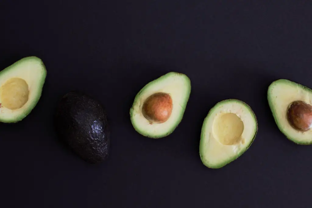 5 Health Benefits of Avocado. Avocado, cut in half on a black table