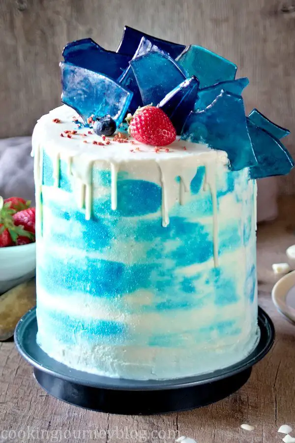 Vanilla Cake Recipe (Birthday Cake Recipe). Sky blue cake, decorated with white chocolate glaze, inserted edible blue glass, strawberry and blueberries.