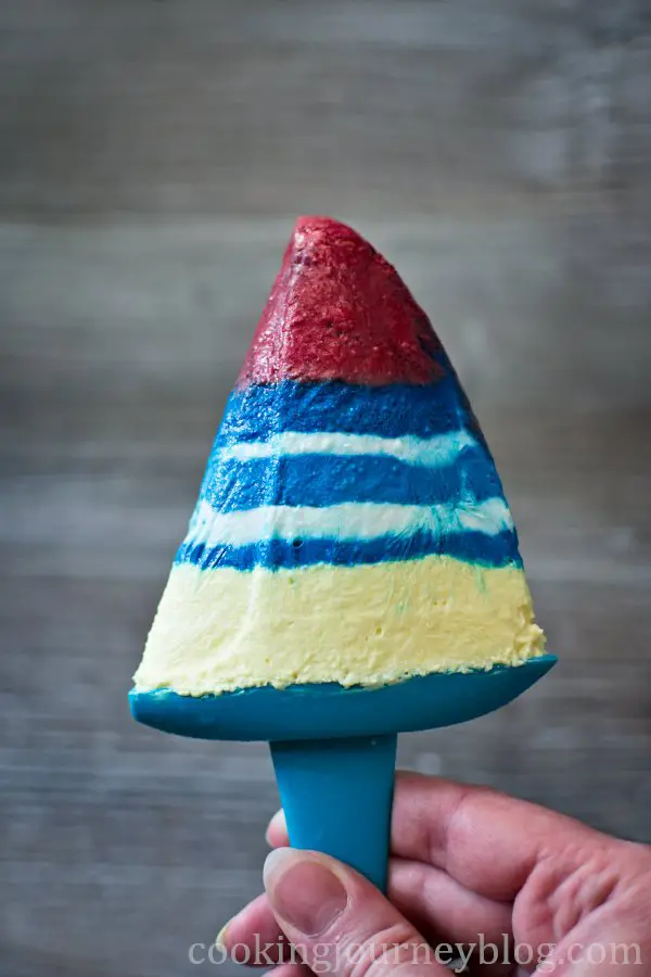 Holding homemade yogurt popsicle with red, blue, white and yellow layers