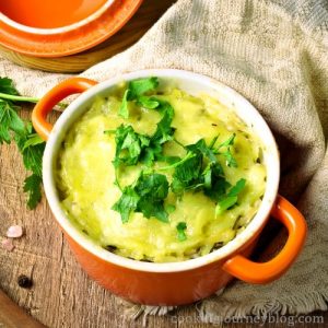 Cheesy hashbrown casserole recipe. Served in an orange pot with parsley