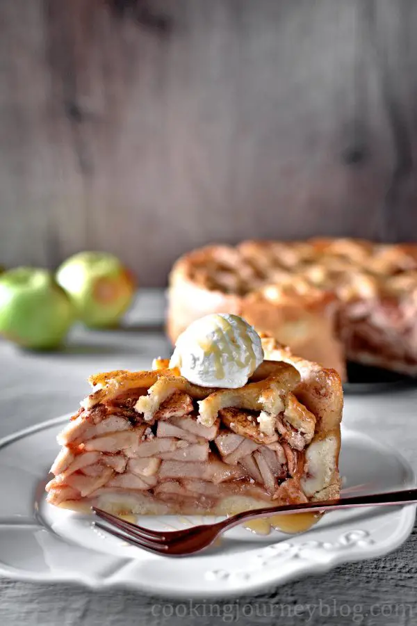 A slice of Traditional Dutch Apple Pie, served on a late with whipped cream