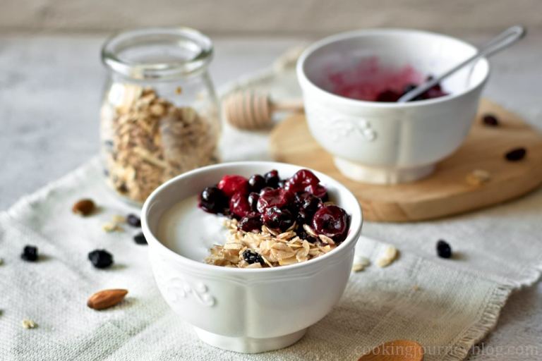 Homemade Granola served with yogurt and berries in a white bowl