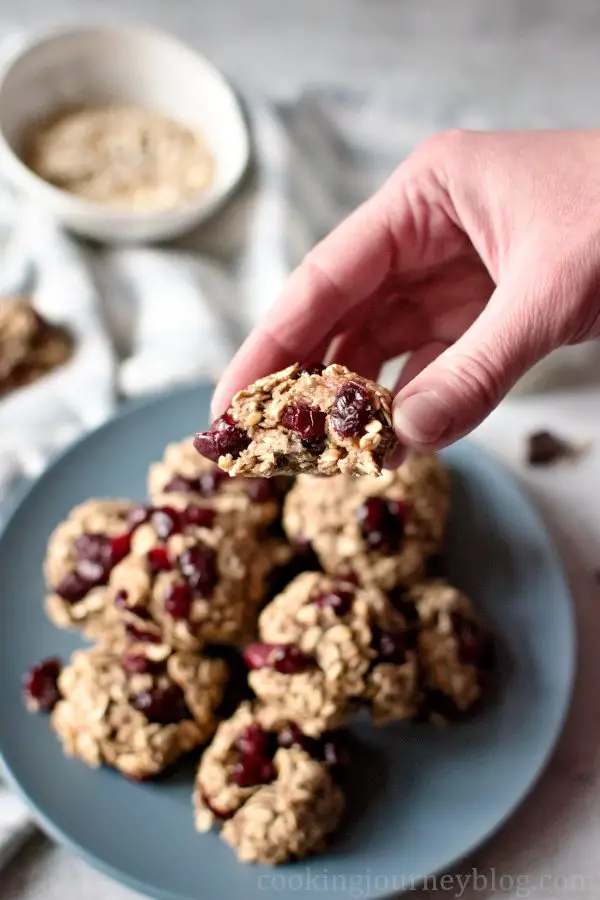 Holding a healthy oatmeal cookie with cranberries in a hand