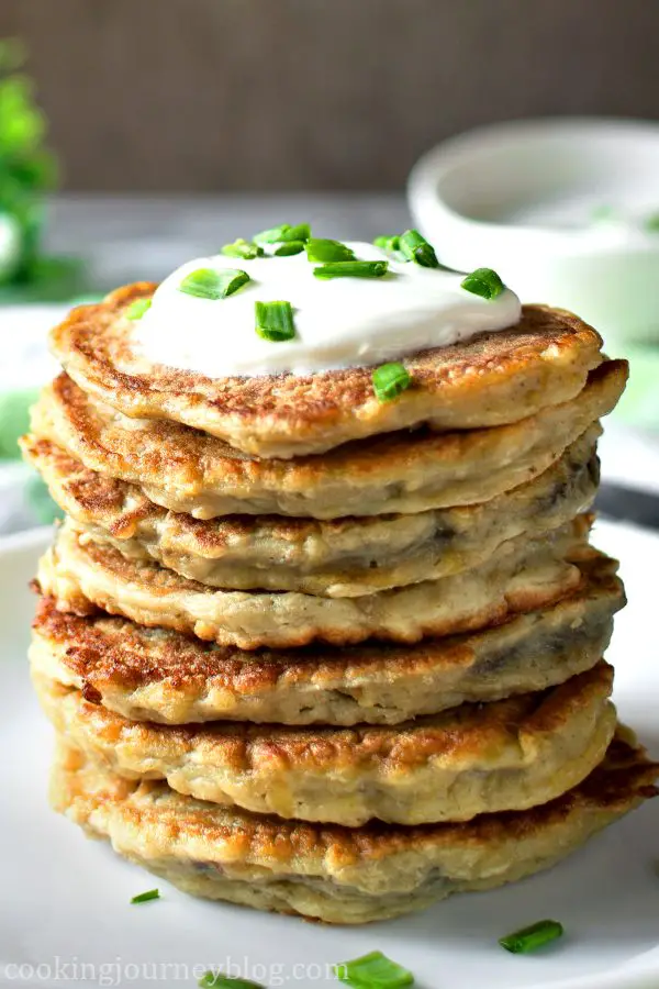 Boxty - Irish Potato Pancakes, stacked on the plate with sour ceam and scallions on top