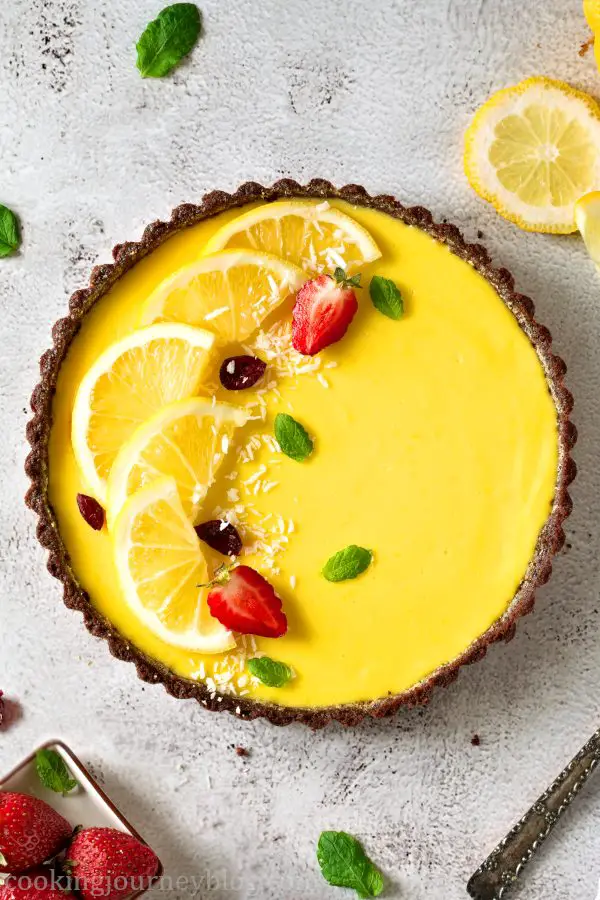 Delightful Lemon Tart with no bake crust, decorated with lemons, strawberry and mint