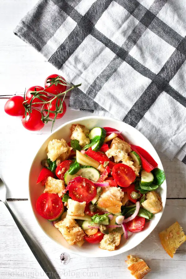 Panzanella salad in a bowl, served with tomatoes on the table