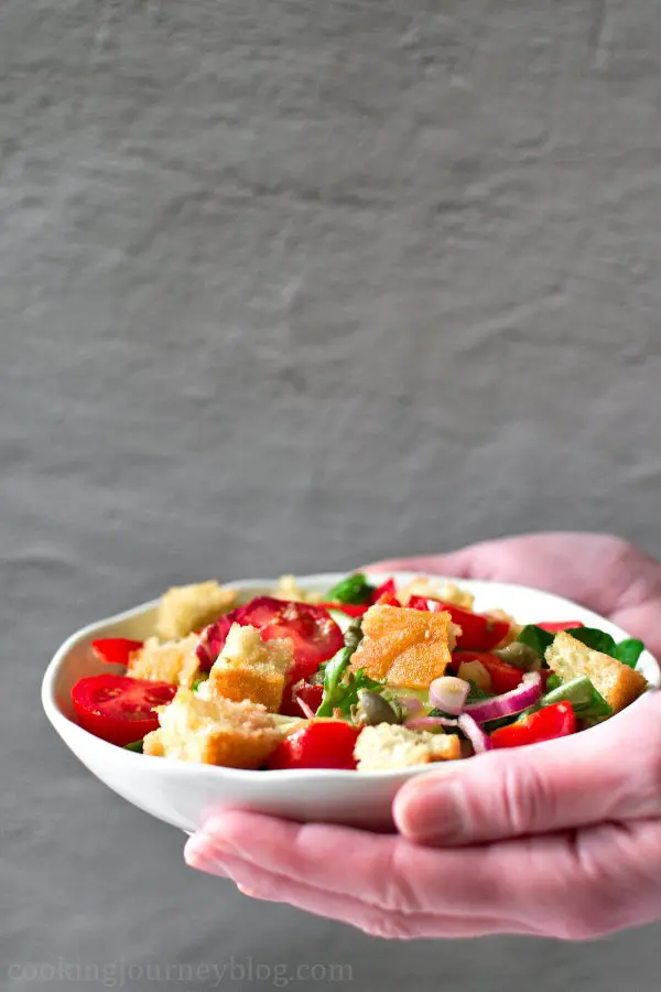 Holding a bowl with panzanella salad in hands