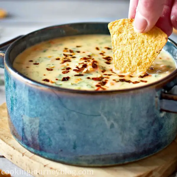 Chile con Queso dip in a blue bowl with tortilla chip.