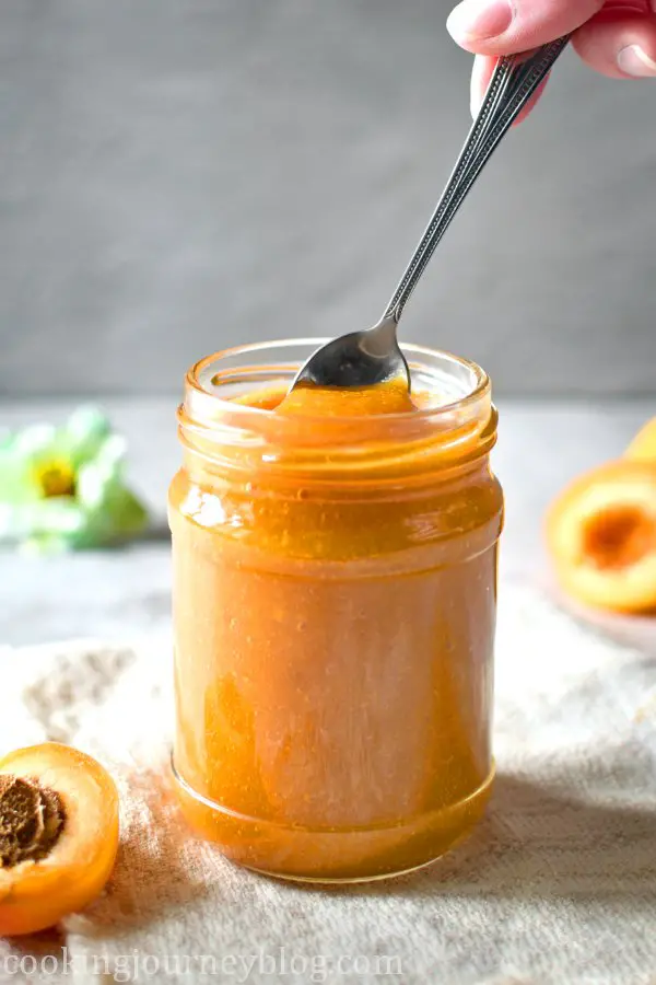 Inserting a spoon in the jar with sugar free apricot jam